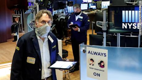 Traders wearing masks work, on the first day of in person trading since the closure during the outbreak of the coronavirus disease on the floor at the New York Stock Exchange.